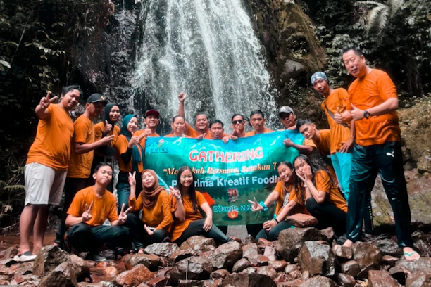 A vibrant group of team members proudly wearing custom printed t-shirts gathered in Kerala's lush outdoor setting.