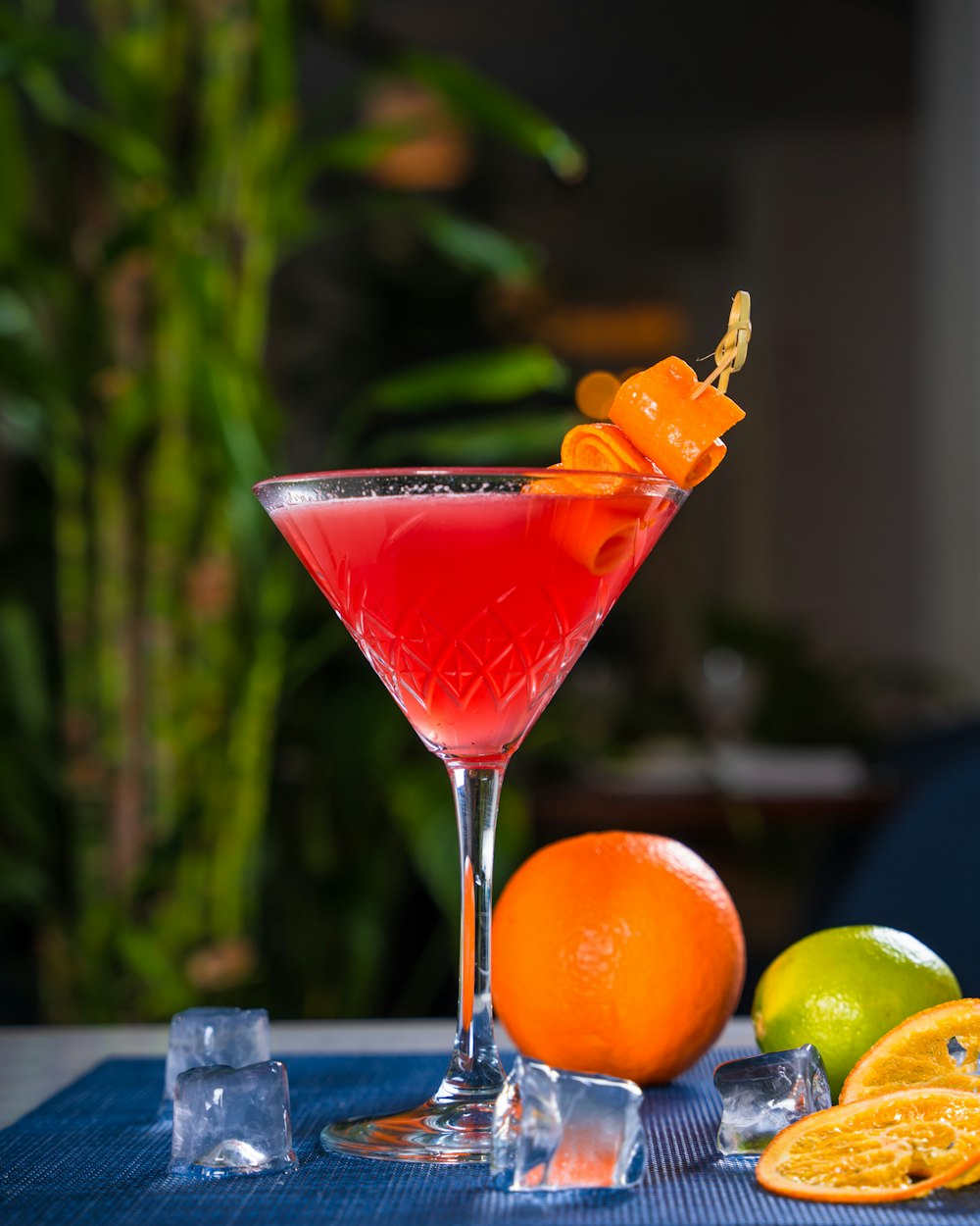 a red cocktail garnished with an orange garnish