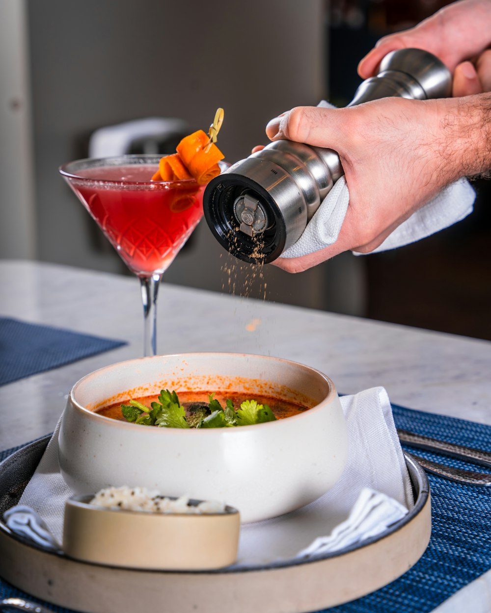 a person pouring a drink into a bowl of soup