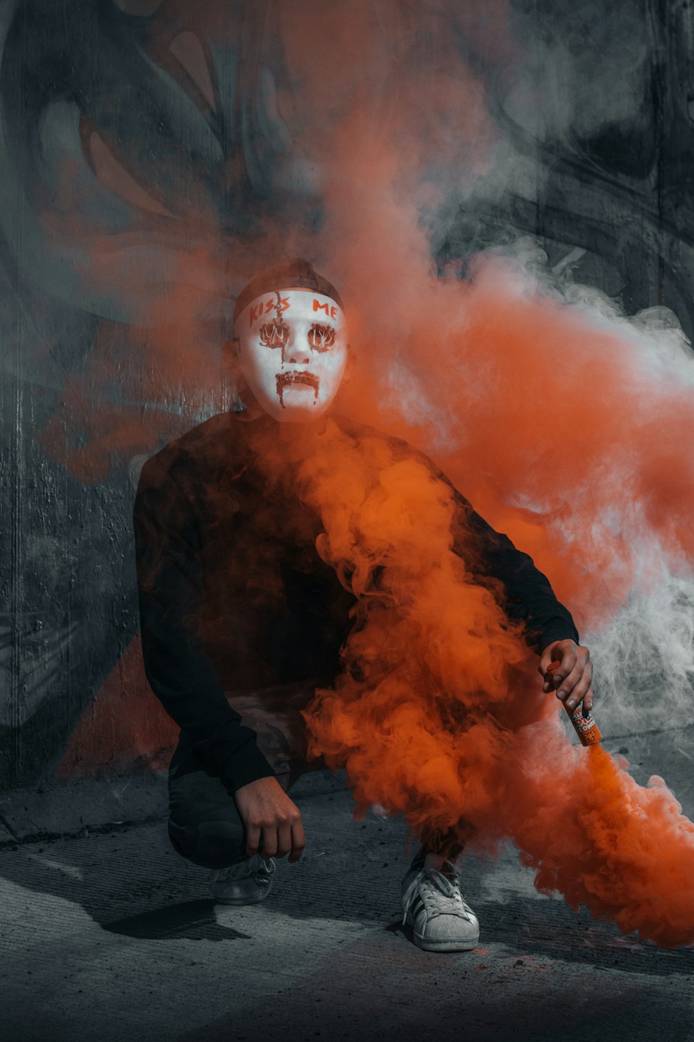 a man with a white face and red smoke behind him