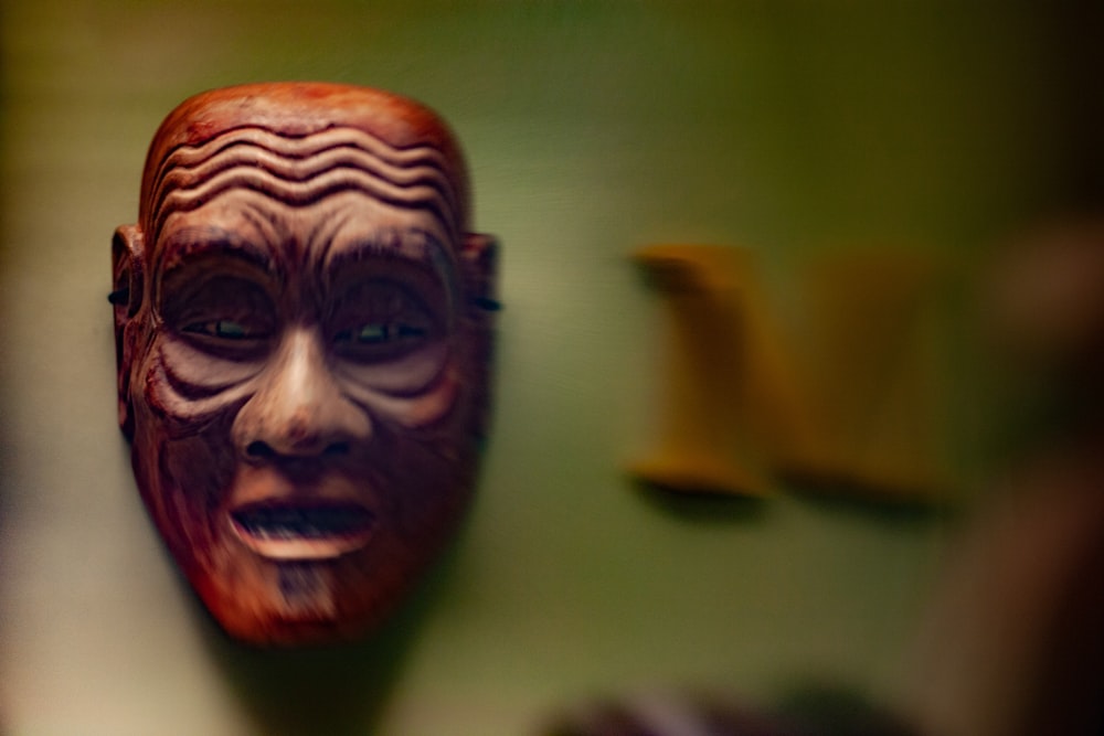 a wooden mask hanging on a green wall