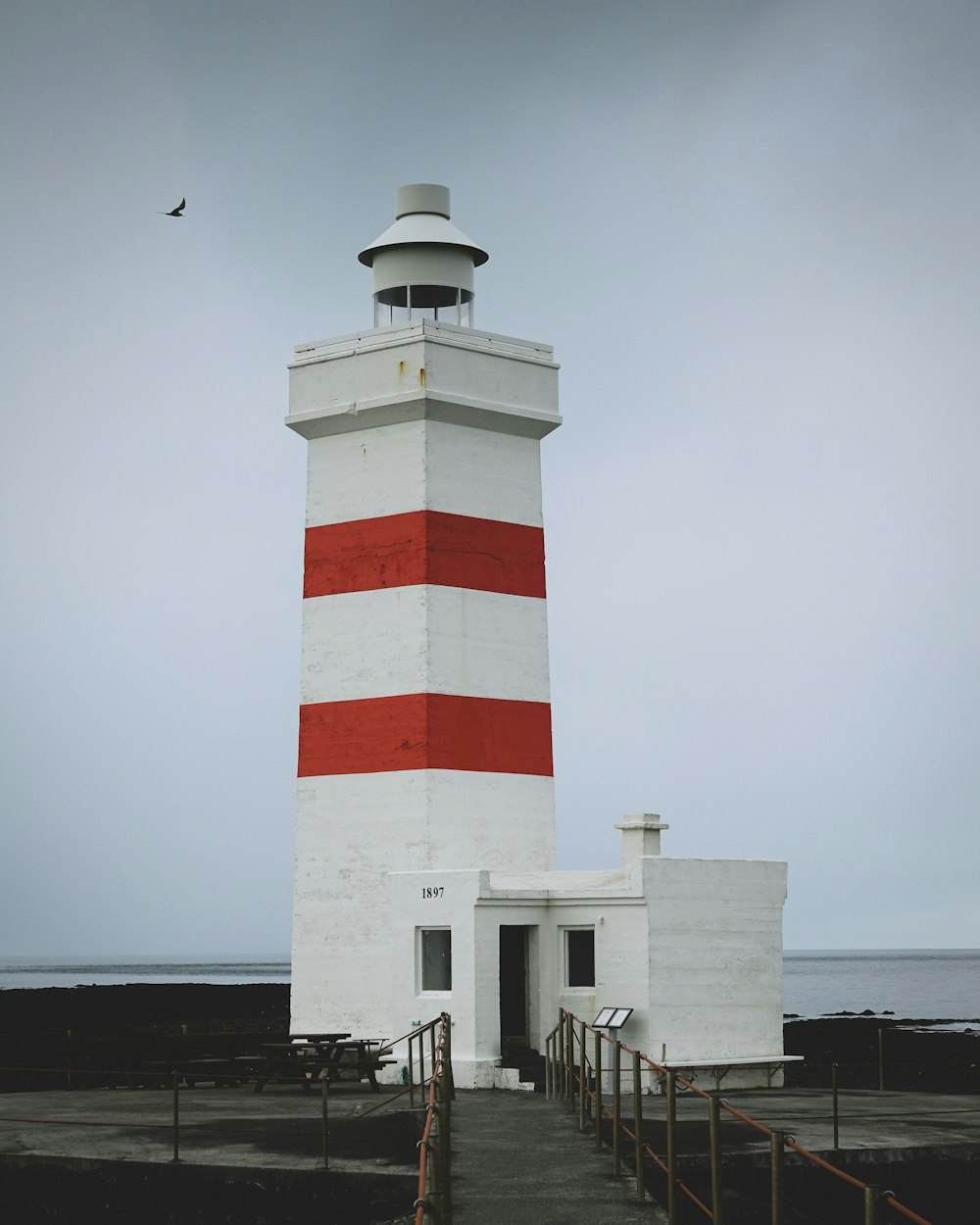 a red and white lighthouse sitting on top of a pier