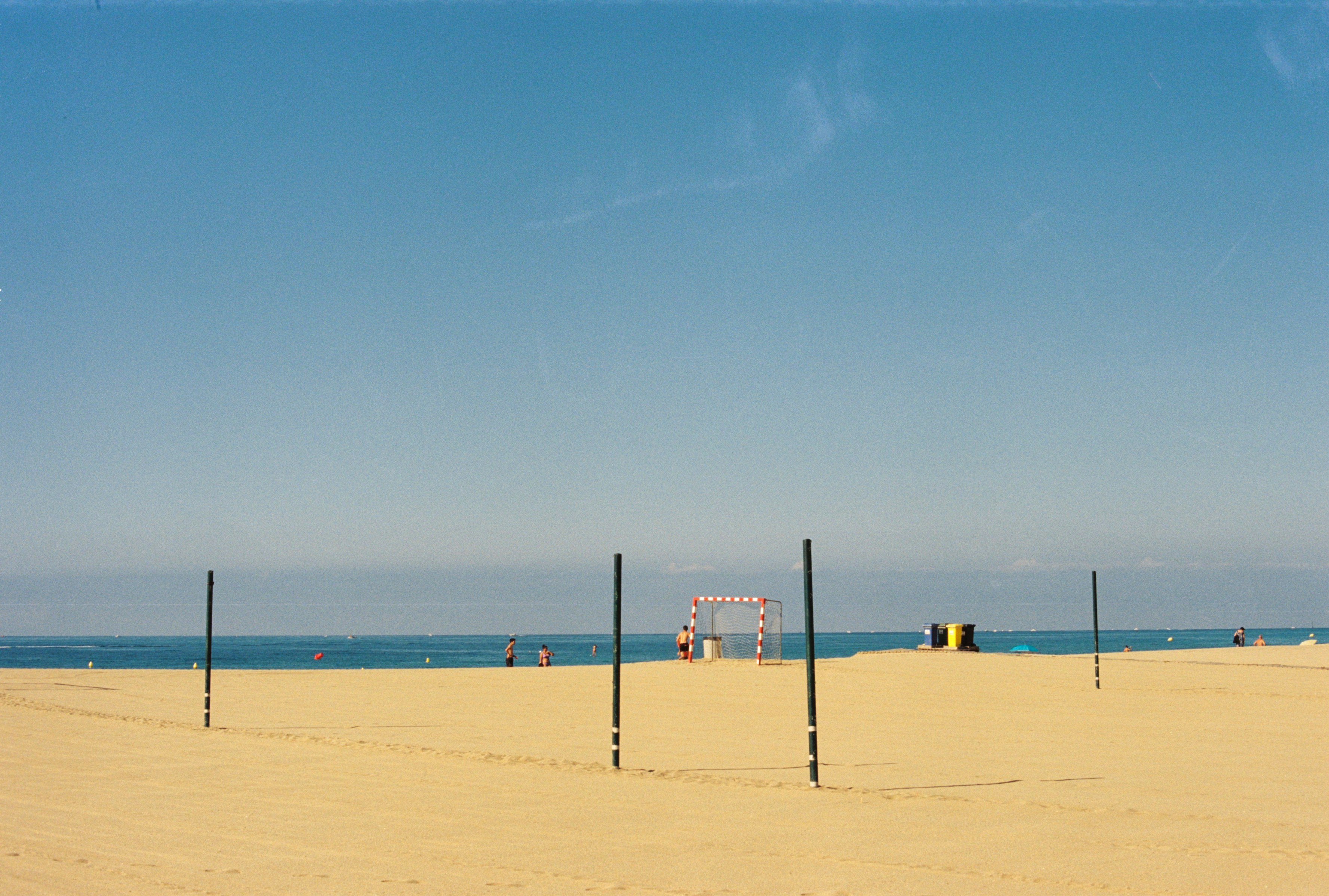 a sandy beach with a volleyball court and a blue sky