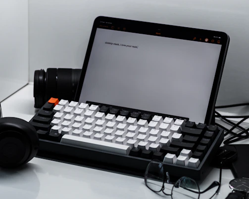 A clean workspace featuring a tablet, keyboard, and mouse with tech review notes visible.