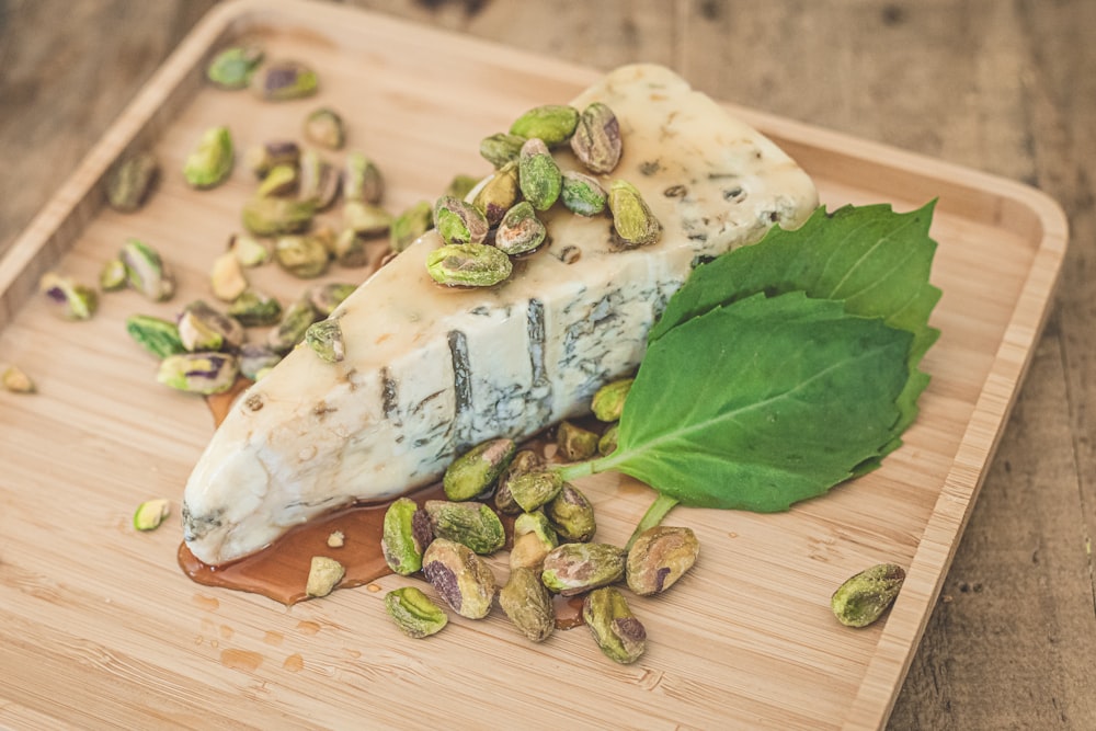 a piece of cheese on a cutting board with a leaf