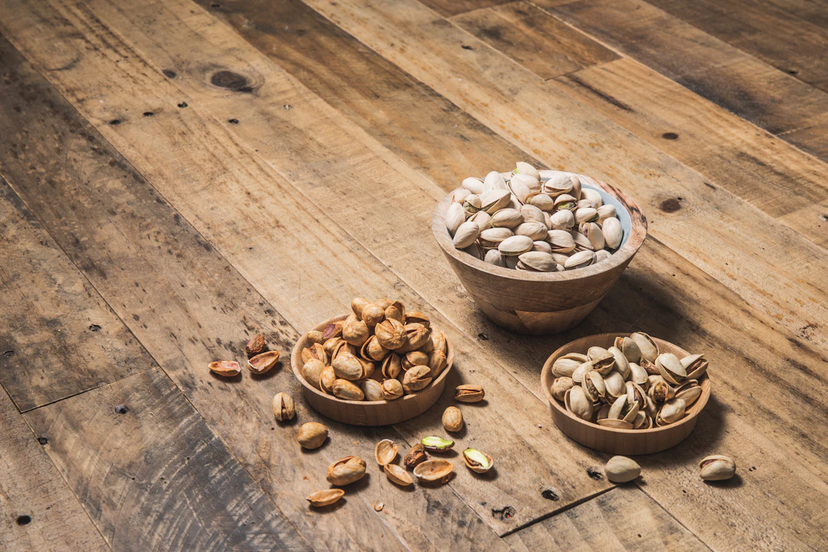 Wooden bowls of pistachios and mixed nuts on a weathered plank bench
