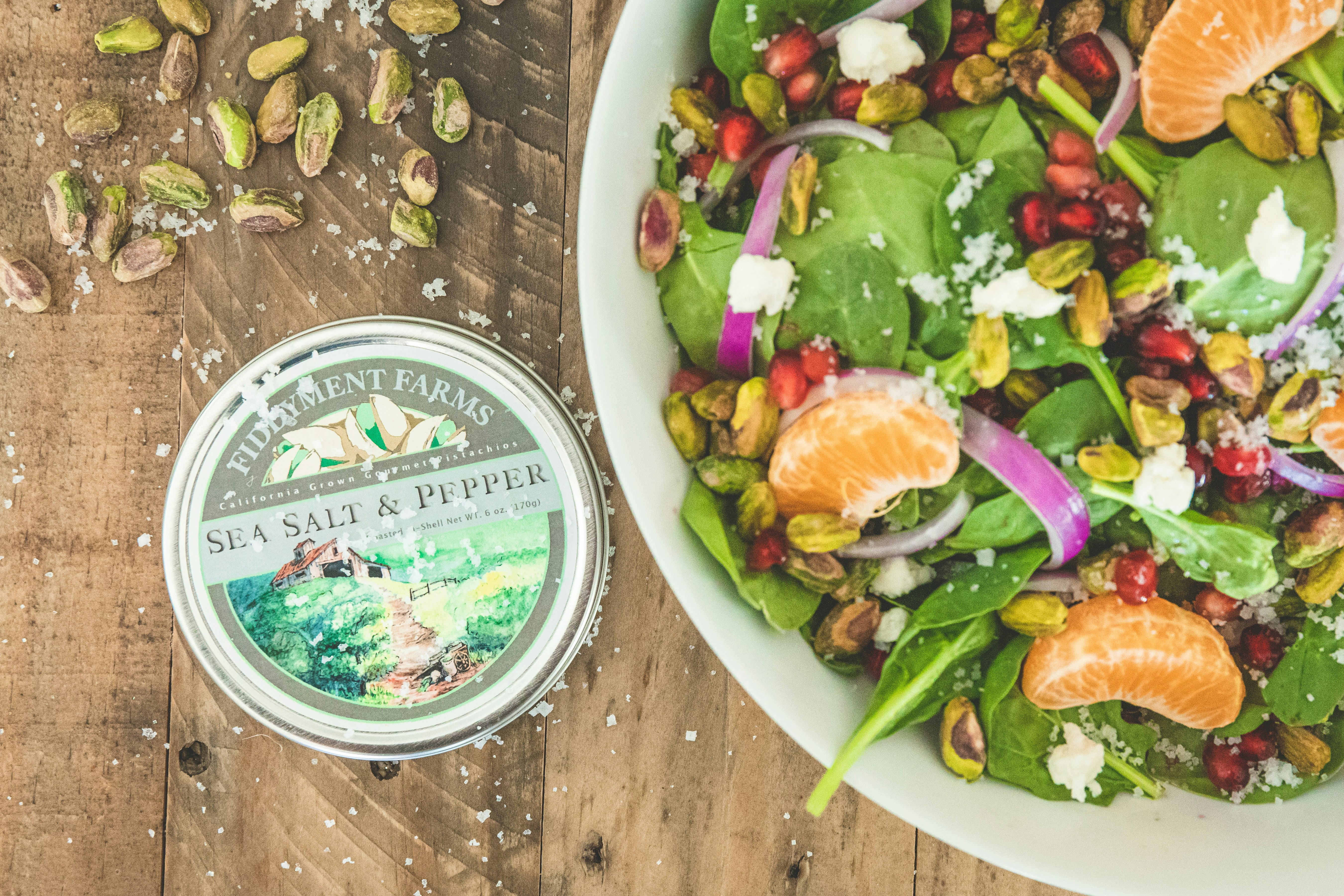 a salad with oranges, spinach, nuts and a tin of sea salt