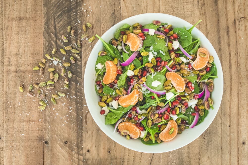 a white bowl filled with a salad on top of a wooden table