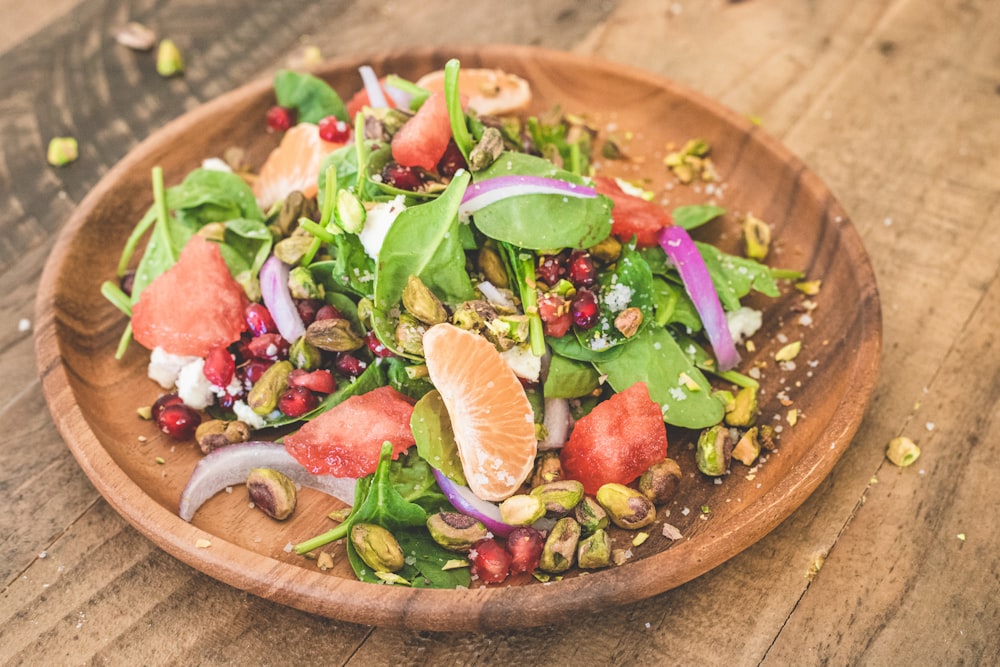 a wooden bowl filled with a salad on top of a wooden table