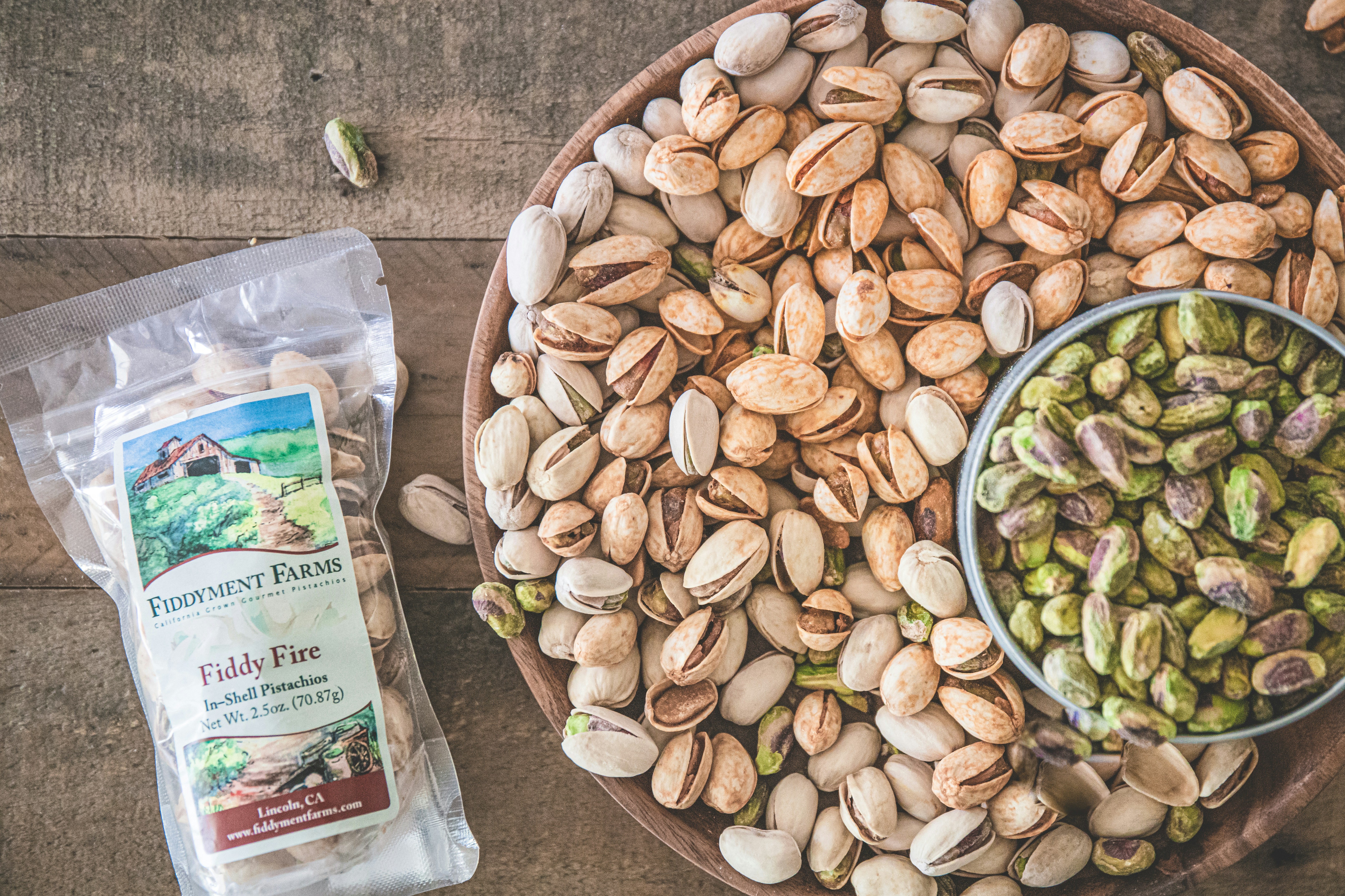 a bowl of nuts next to a bag of peanuts