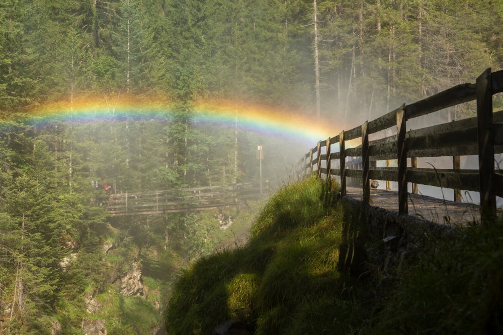uma ponte de madeira com um arco-íris no fundo