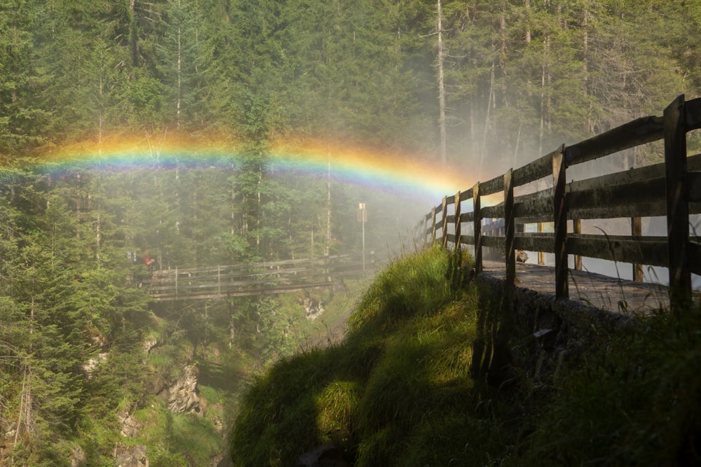 Un pont en bois avec un arc-en-ciel en arrière-plan