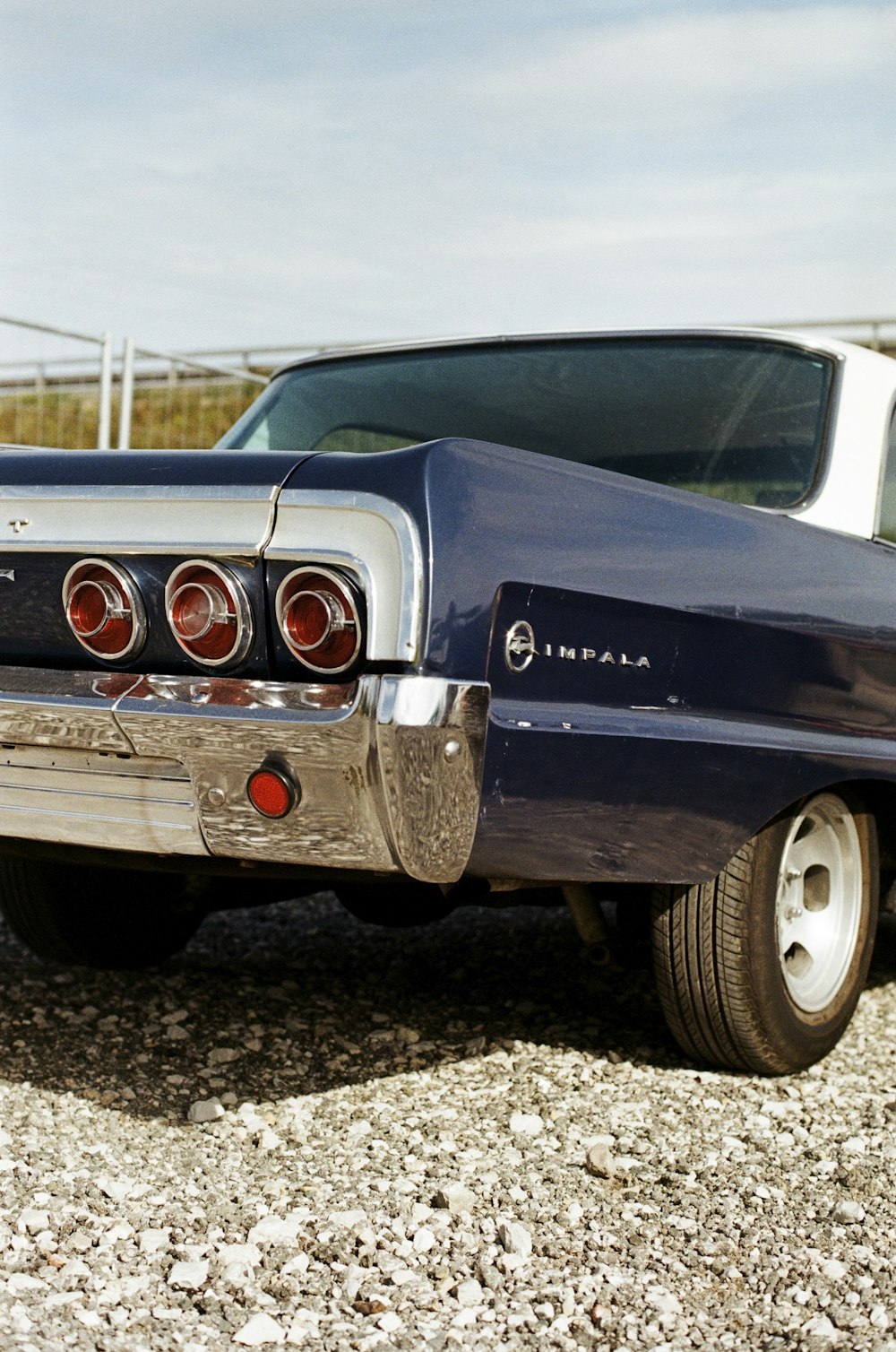 a blue car parked on top of a gravel field