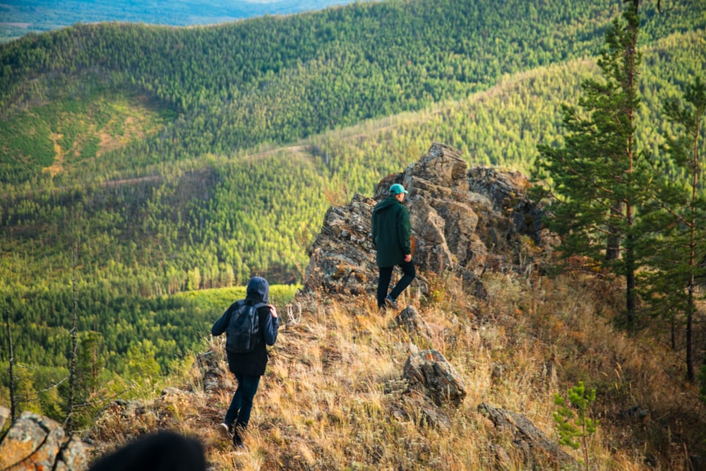 a couple of people walking up the side of a mountain