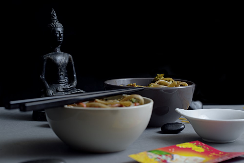 a table topped with bowls of food and a statue