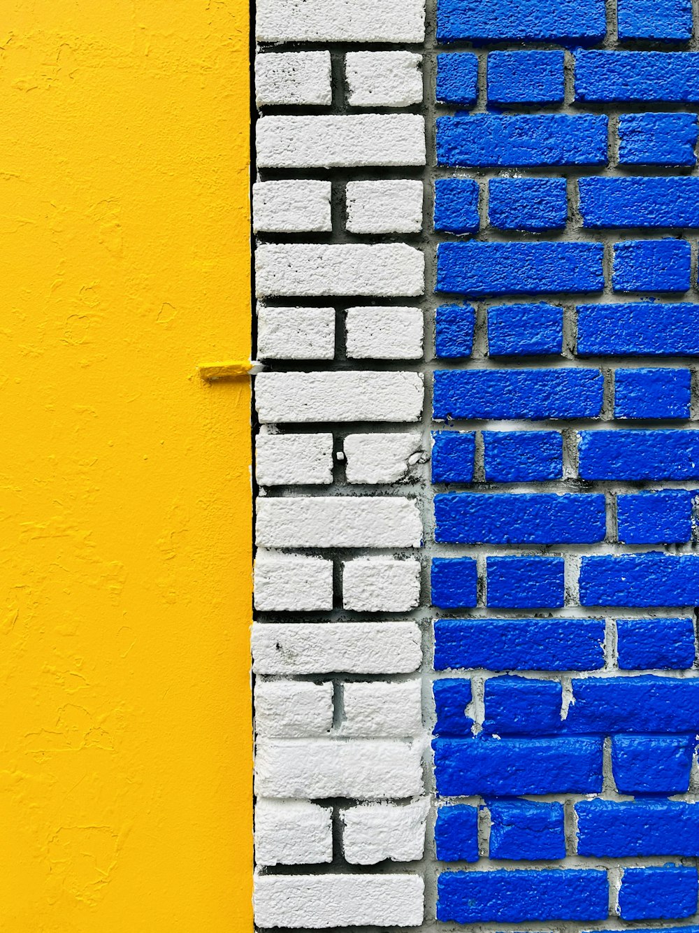 a close up of a brick wall painted blue and yellow