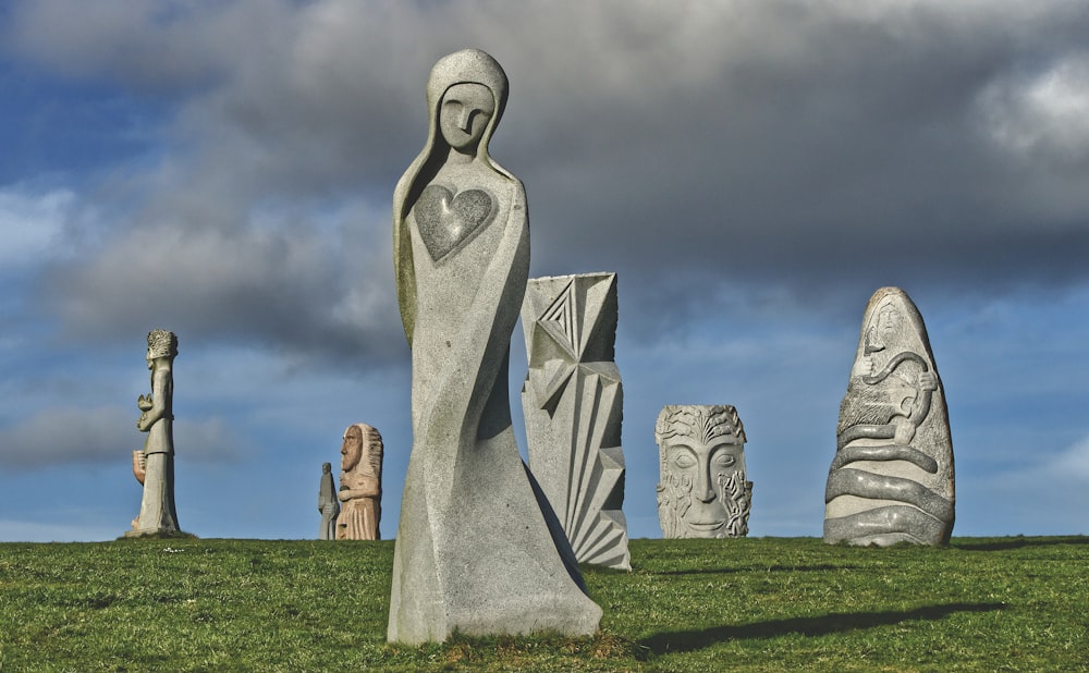 Una estatua de una mujer parada frente a un grupo de estatuas