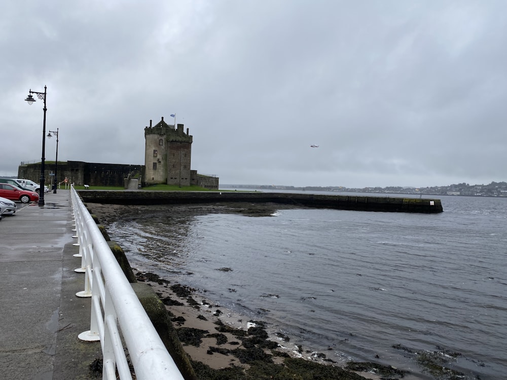 a large body of water next to a white fence