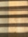 Wooden flooring with alternating vertical slats on the left side. Shadows cast across the surface, creating a pattern of light and dark bands.
