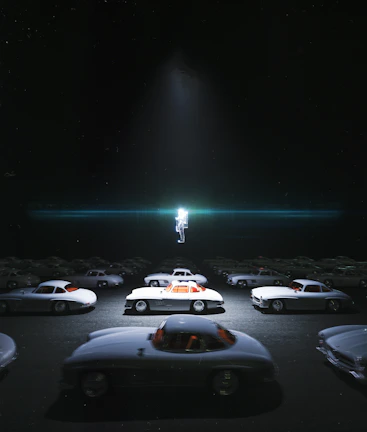 A group of retro cars lined up against a backdrop of a starry night sky and a giant rocket sculpture.