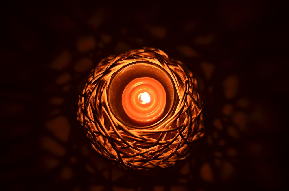 a lit candle in a wicker basket in the dark