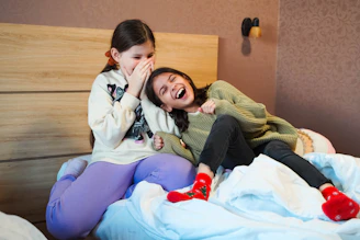 a couple of girls sitting on top of a bed