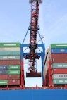 Workers carefully loading large glass sheets onto a shipping container at an industrial port.
