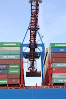 Workers carefully loading large glass sheets onto a shipping container at an industrial port.