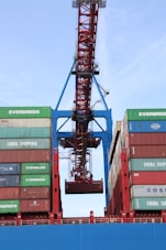 A rugged crane maneuvering heavy cargo containers at a busy shipping port.
