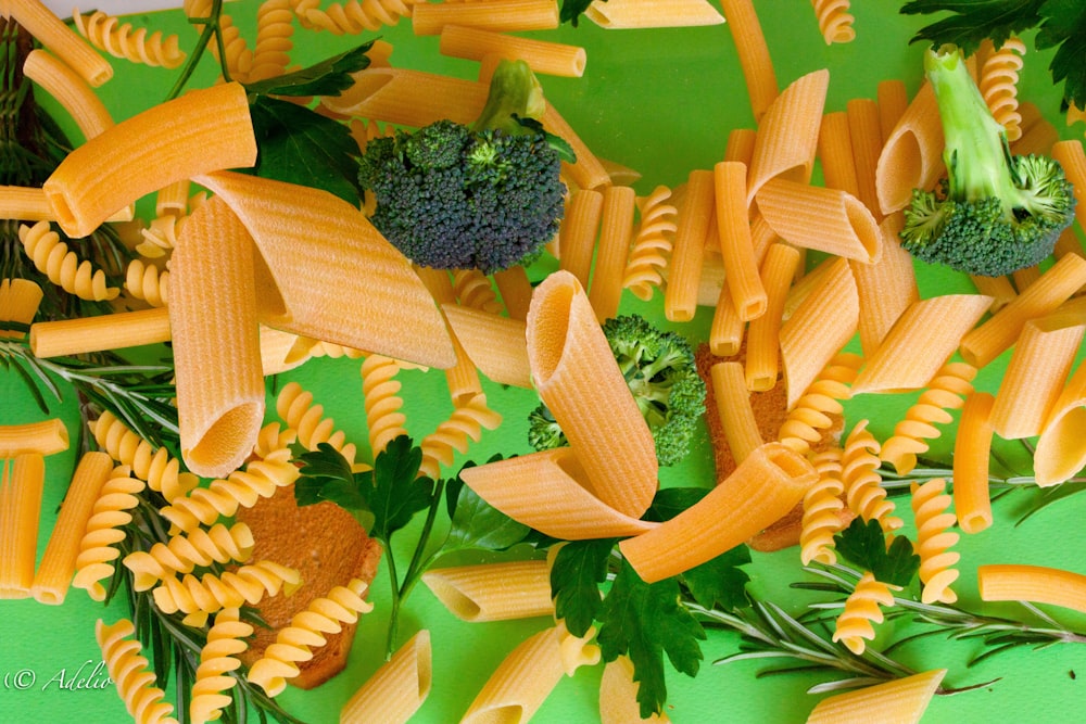 a pile of pasta and broccoli on a green surface