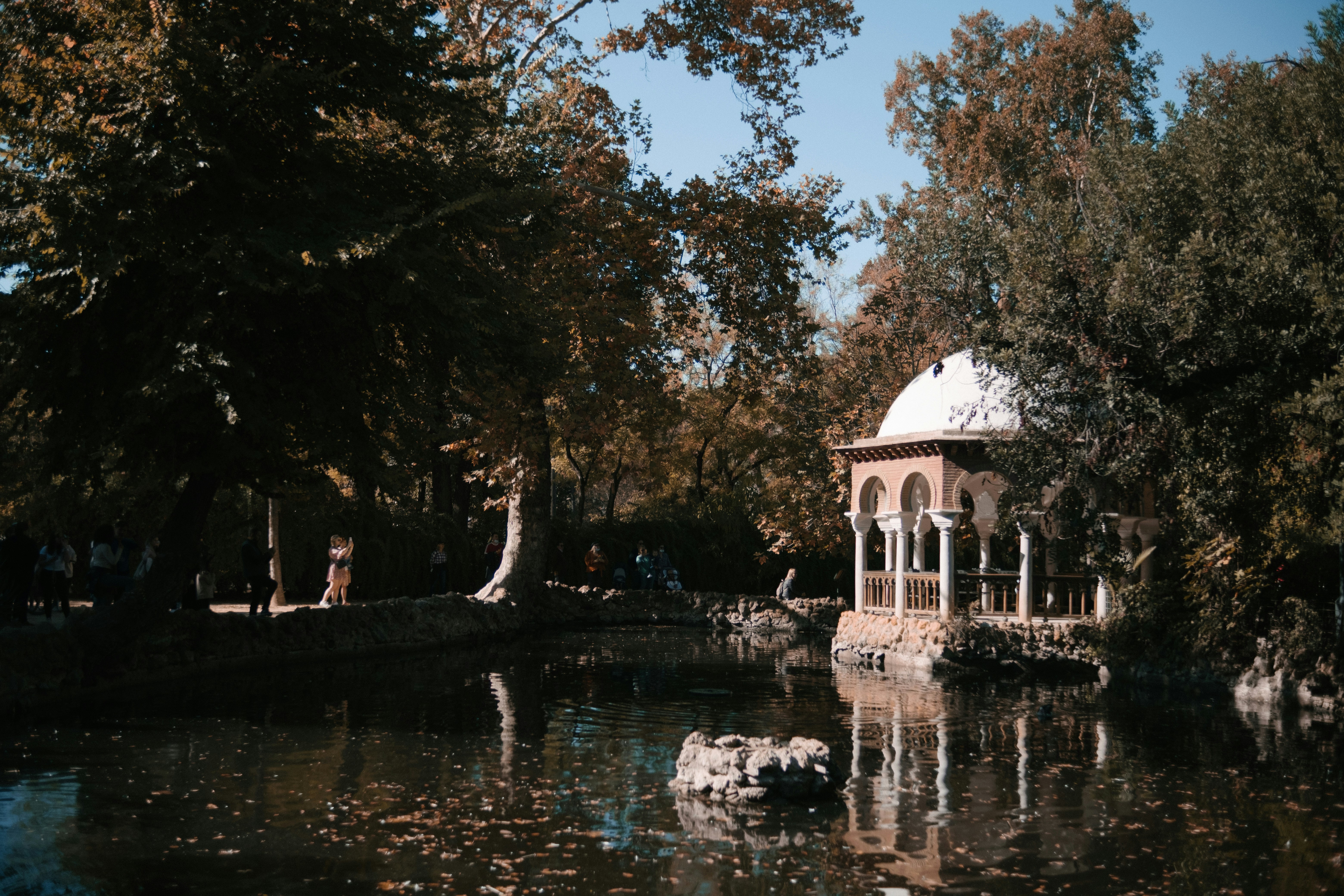 a gazebo in the middle of a pond surrounded by trees
