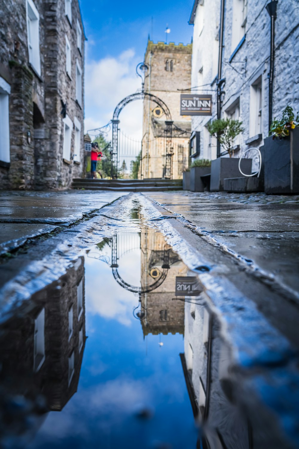 a reflection of a clock tower in a puddle of water