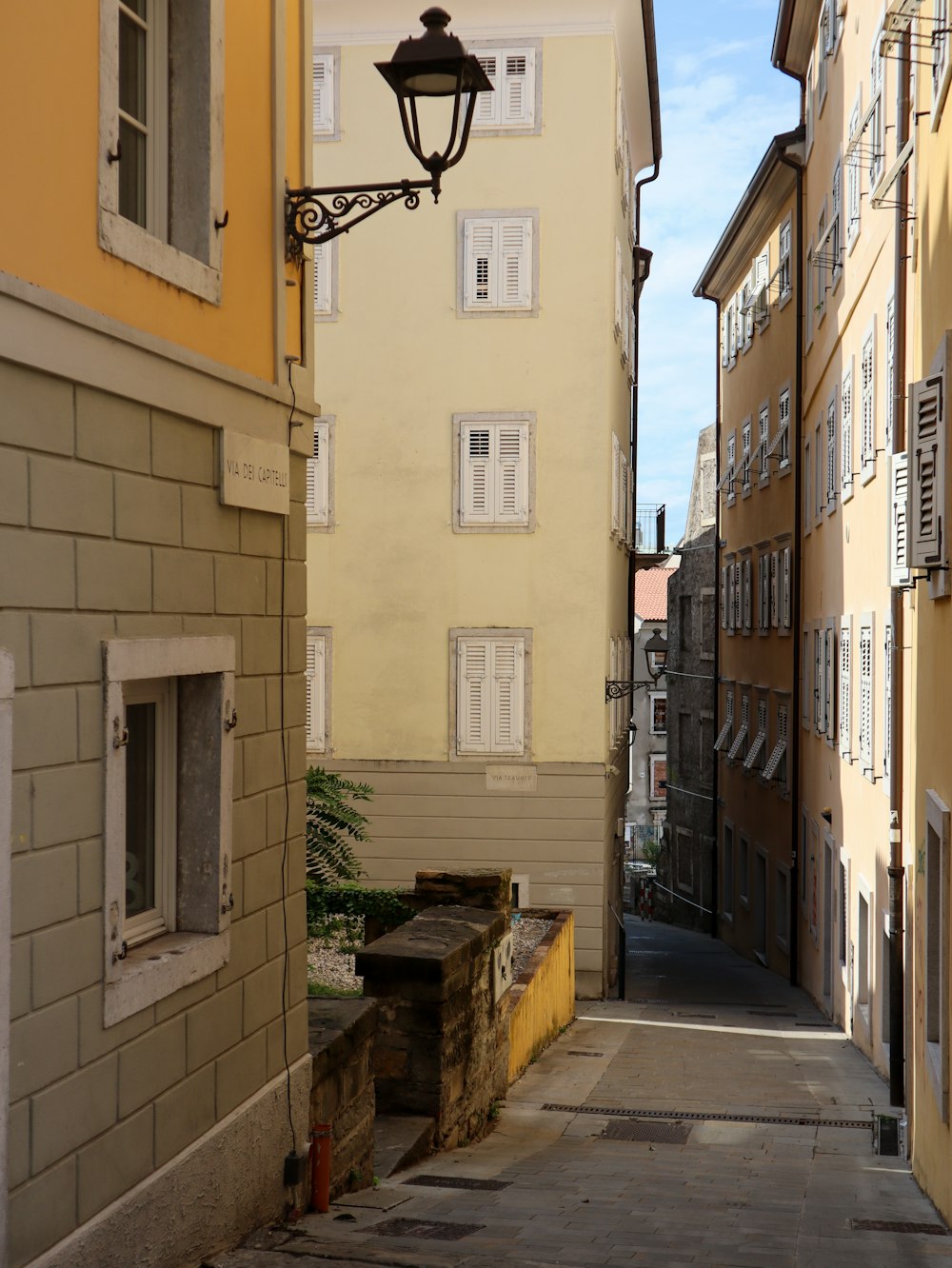 a narrow alley way with a lamp on the side