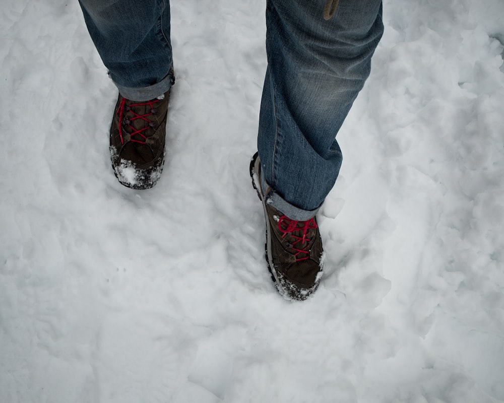 a person standing in the snow wearing hiking boots