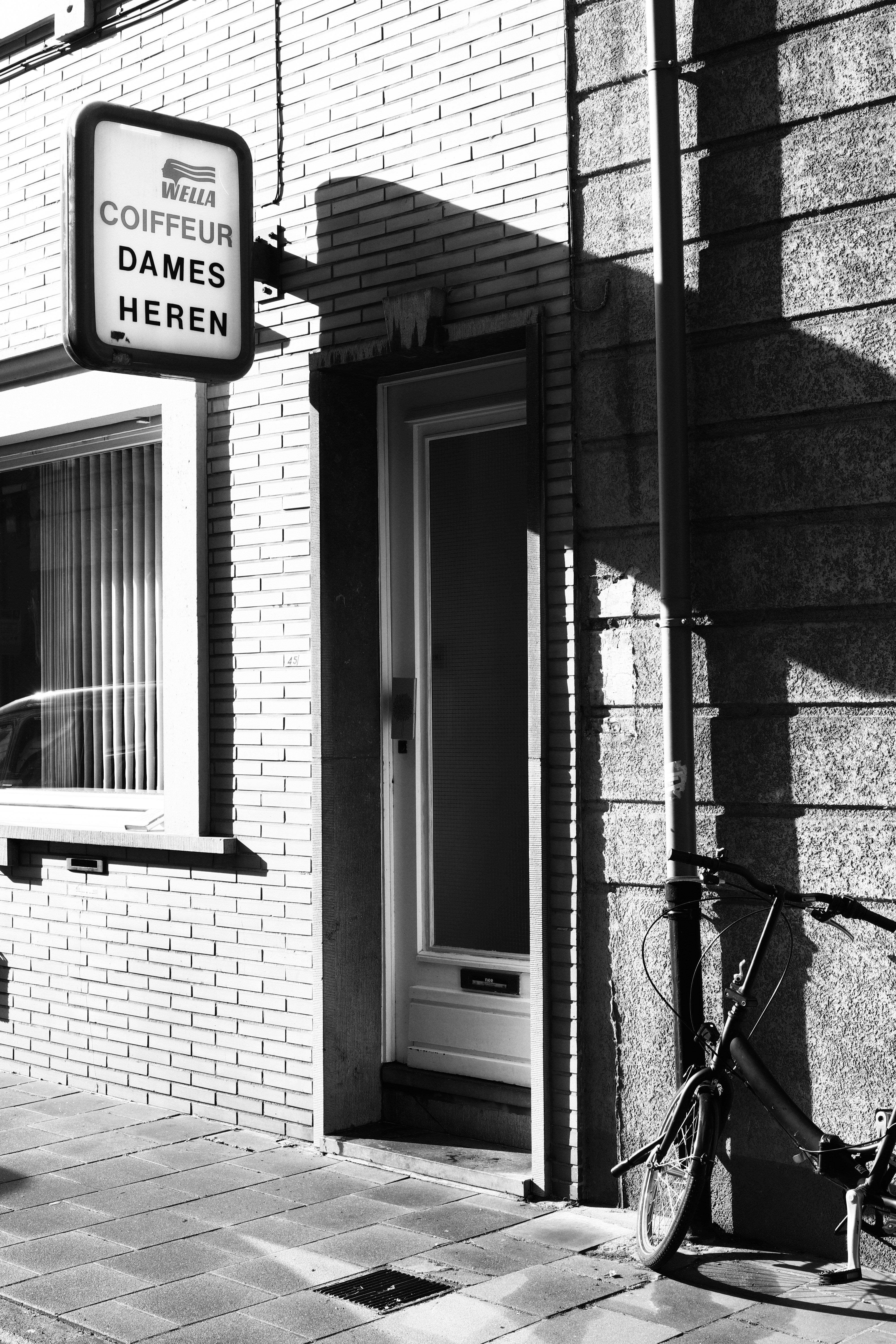 a black and white photo of a bike parked in front of a building