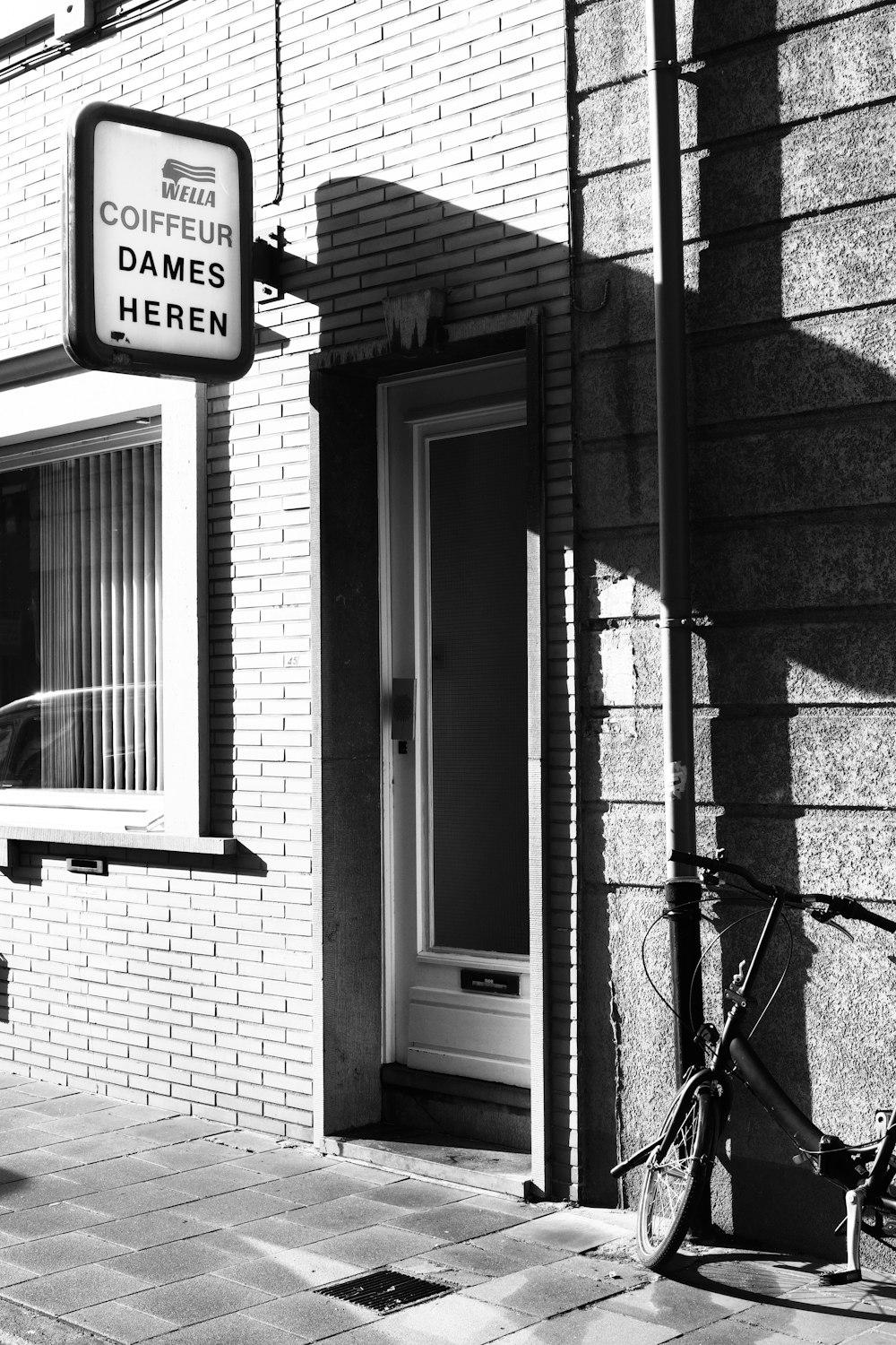 a black and white photo of a bike parked in front of a building