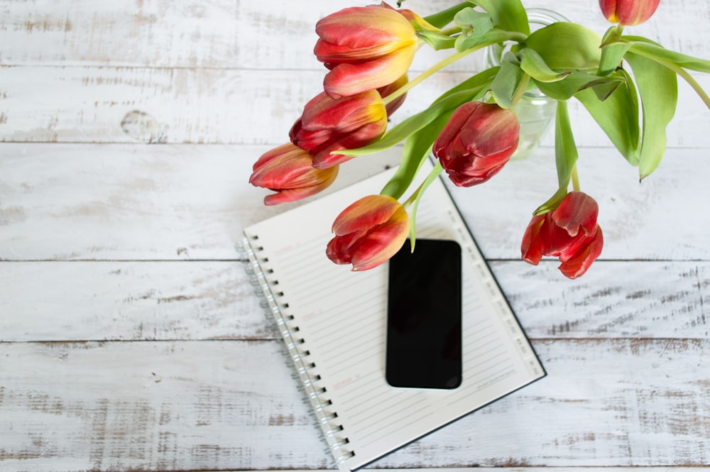 a notebook with a pen and a bunch of tulips