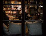 Warm-lit bookstore interior with customers browsing and chatting among shelves.
