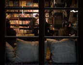 Warm-lit interior of Imagine Books Shop with customers browsing and chatting.