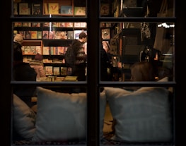 Warm-lit interior of Imagine Books Shop with customers browsing and chatting.
