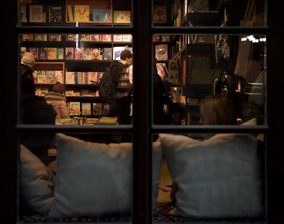 A smiling customer browsing through a stack of novels near a large window.
