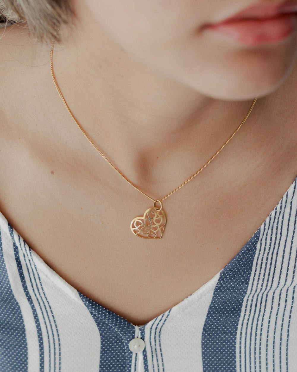 a woman wearing a necklace with a heart on it