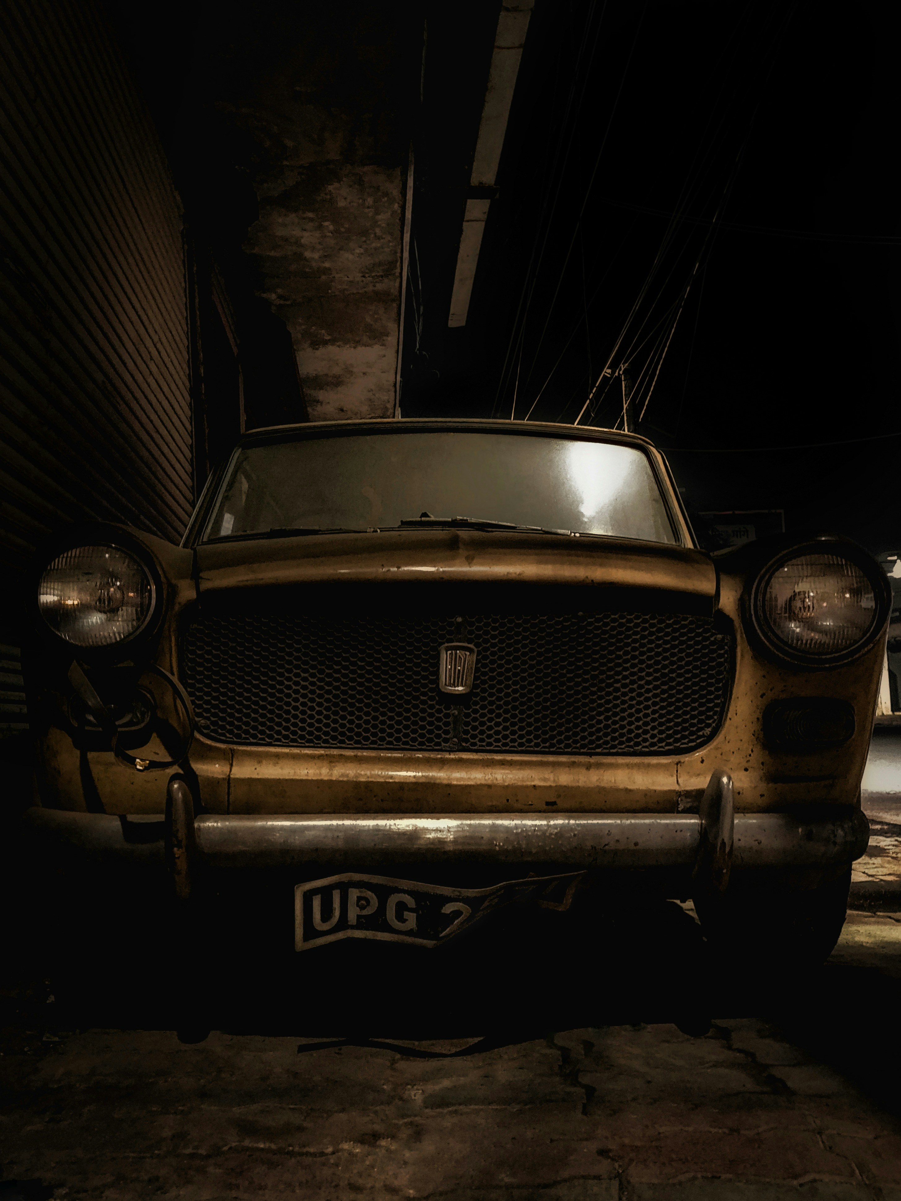 an old car is parked in a dark alley