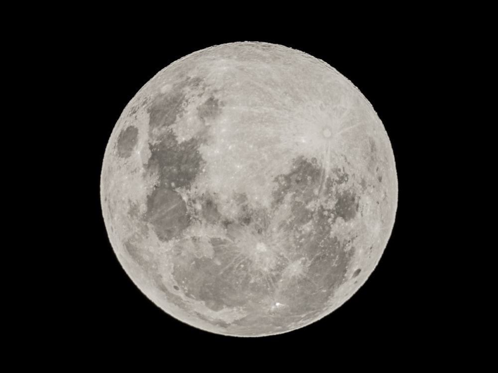 a full moon is seen in the dark sky