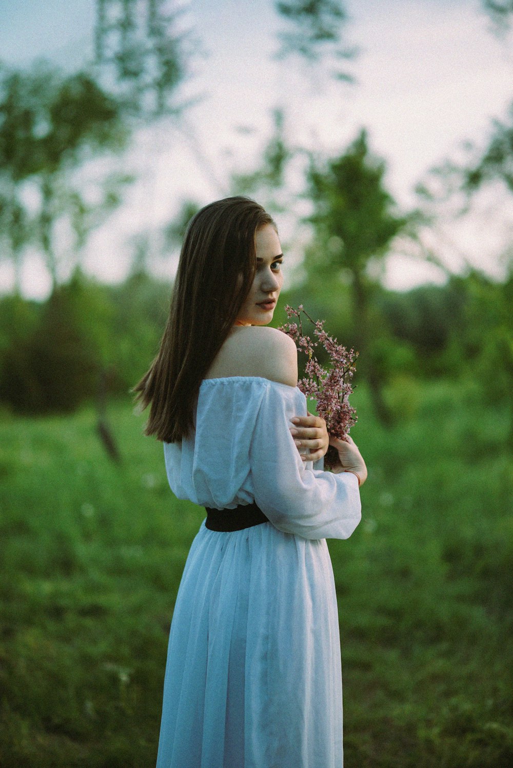 Una mujer con un vestido blanco sosteniendo una flor