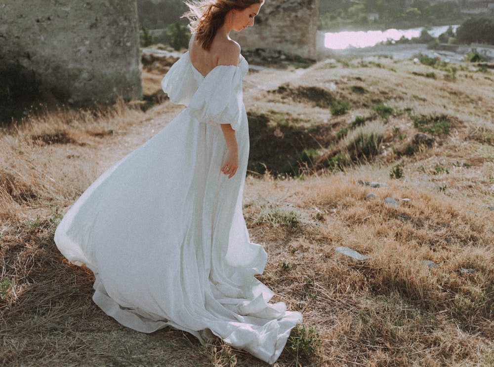 a woman in a white dress standing in a field