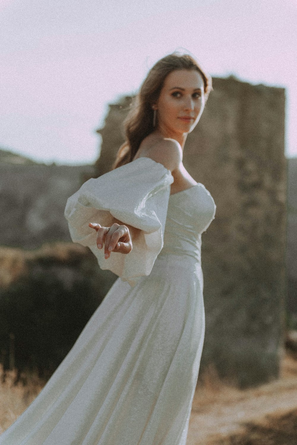 a woman in a white dress standing in a field