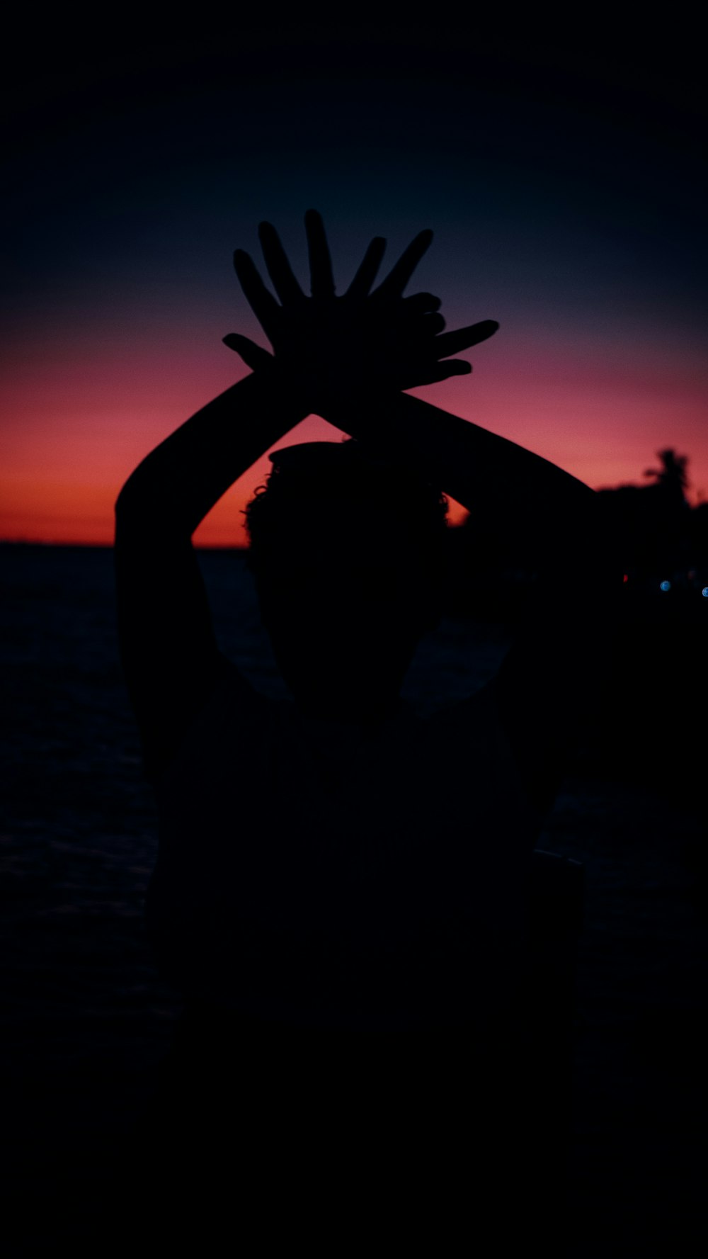 a silhouette of a person holding their hands up in the air