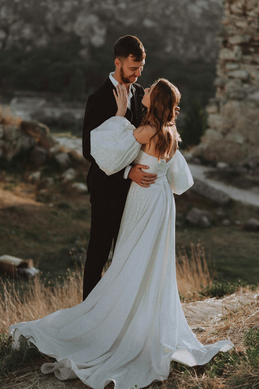 a bride and groom standing in a field