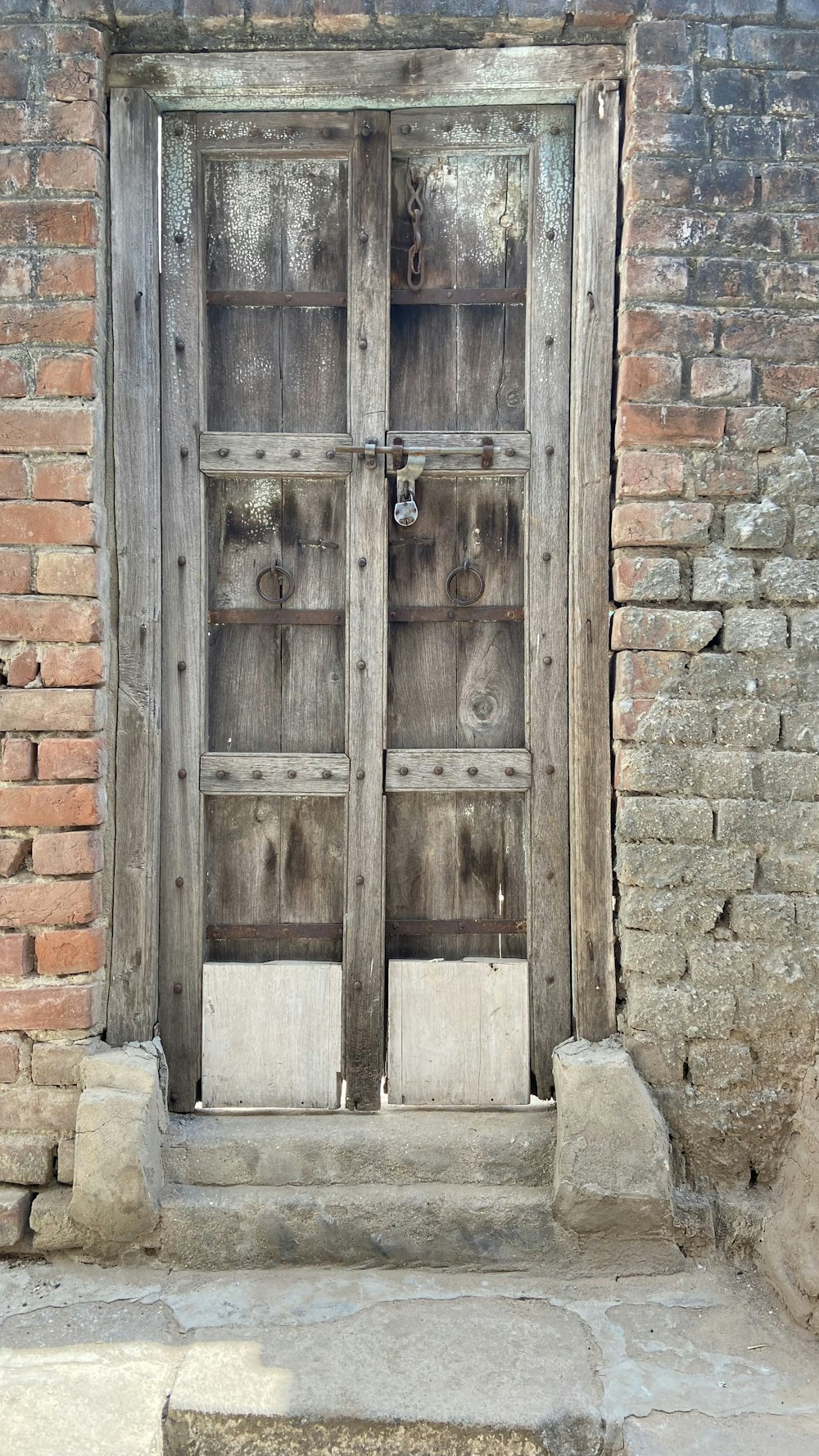 a wooden door with a brick wall behind it